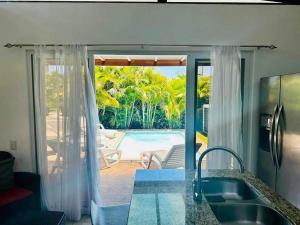 a kitchen with a view of a pool from a house at Lapa House 4 ( Cozy pool-3 bedrooms(LL#4) in Jacó