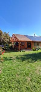 una casa con un patio de hierba delante de ella en Refugio Wanglen Cabañas y Tinajas hidromasaje, en Lago Ranco