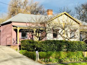a pink house with a hedge in front of it at Quarryman Cottage @ 102 in Bowral
