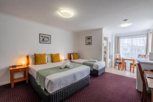 a hotel room with two beds and a table and chairs at The Henry Parkes Tenterfield in Tenterfield