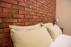 een bed met twee kussens tegen een bakstenen muur bij Kisetsu no ie, KLCC Kuala Lumpur in Kuala Lumpur