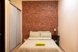 een bed in een kamer met een bakstenen muur bij Kisetsu no ie, KLCC Kuala Lumpur in Kuala Lumpur