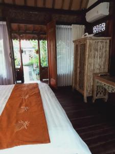 1 dormitorio con cama, mesa y ventanas en Buratwangi Joglo House, en Kerobokan