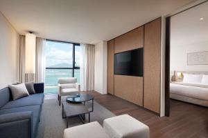 a living room with a couch and a bed and a television at Shilla Stay Yeosu in Yeosu