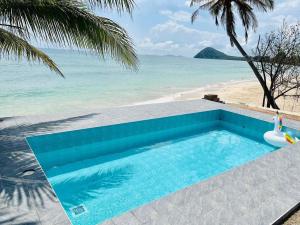 a swimming pool next to a beach with the ocean at MD Pool Villa Chumphon in Ban Tha Samet (1)