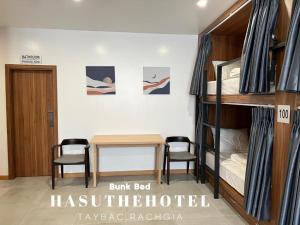 Hasu The Hotel في راش غايا: غرفة مع سرير بطابقين وطاولة وكراسي