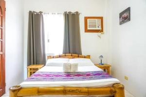 1 dormitorio con cama con marco de madera y ventana en Baki Divers and Beach Resort, en Dauin