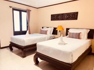 um quarto com 2 camas e uma janela em Na Thapae Chiangmai Hotel em Chiang Mai