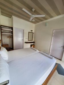 a large white bed in a room with a ceiling at Sun & Surf in Thulusdhoo