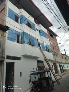 mężczyzna na drabinie malujący bok budynku w obiekcie Casa Alojamiento Virreynal w mieście San Ramón