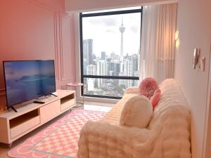 a child sitting on a couch in a living room with a television at The Ress - The Axon Bukit Bintang Residence in Kuala Lumpur