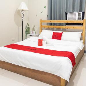 1 dormitorio con 1 cama grande con almohadas blancas y rojas en P3K Suites Budget Hotel en Manila