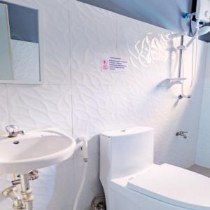 Baño blanco con lavabo y aseo en P3K Suites Budget Hotel en Manila