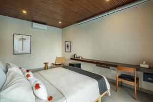 a bedroom with a large bed and a desk at Villa Olea in Uluwatu