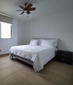 a white bedroom with a bed and a ceiling fan at Habitación privada en zona exclusiva in Panama City