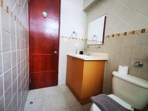 ein Bad mit einem WC, einem Waschbecken und einer roten Tür in der Unterkunft Habitación privada en zona exclusiva in Panama-Stadt