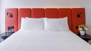 1 cama con almohadas blancas y cabecero rojo en Elysia Wellness Retreat, en Pokolbin