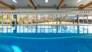 a large swimming pool in a building with a large window at Elysia Wellness Retreat in Pokolbin