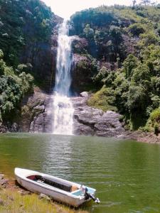 een boot in het water voor een waterval bij Rock View Rest Hatton in Hatton