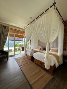 a bedroom with two beds with white drapes at Atres Sari Resort in Munduk