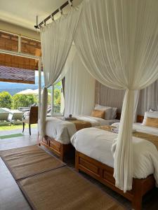 a bedroom with two beds with white drapes at Atres Sari Resort in Munduk