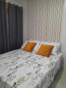 a bed with two orange pillows on top of it at The Hideaway at Citta Verde Primavera City in Cagayan de Oro