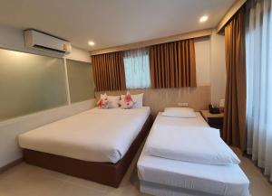 a bedroom with two beds and a window at Malee Hotel in Chiang Mai