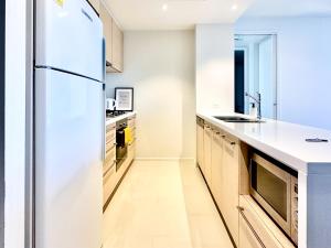 a kitchen with white counters and a refrigerator at Luxurious 2 Bed Apartment with Captivating View in Melbourne +8 photos