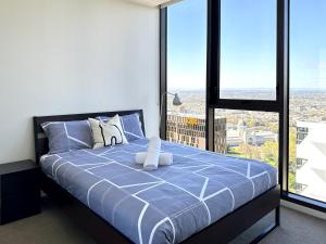 a bedroom with a bed with a view of a city at Luxurious 2 Bed Apartment with Captivating View in Melbourne