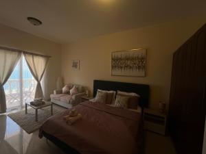 1 dormitorio con cama, sofá y ventana en Full sea view Studio high floor, en Ras al Khaimah