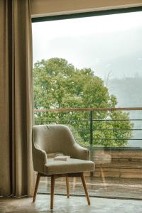 a chair sitting in front of a large window at Moganshan Spring Mountain View B&B in Deqing