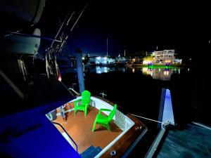 a boat with two green chairs on the deck at night at Beautiful Floating Stay in Marathon