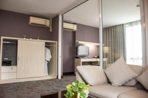 a living room with a couch and a tv at Chor Cher The Luxury Green Hotel - SHA Extra Plus in Bang Bo
