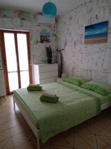 um quarto com uma cama com lençóis verdes e uma janela em Appartamento Via Pitagora em Scalea