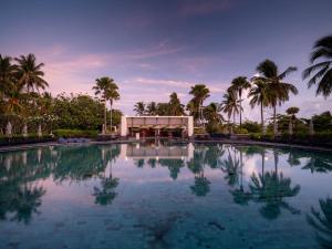 a pool with palm trees in front of a building at Pullman Phuket Karon Beach Resort in Karon Beach