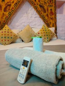 - une télécommande assise sur un lit avec une couverture dans l'établissement Martine guest house, à Jaisalmer