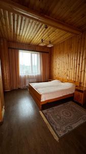 una camera da letto con un grande letto in una camera in legno di Osobnyak a Shchuchinsk