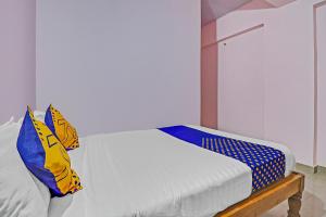 1 dormitorio con 1 cama con almohadas azules y amarillas en SPOT ON Sln Comforts Near Nagasandra Metro Station, en Bangalore