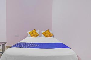 Una cama blanca con almohadas amarillas y azules. en SPOT ON Sln Comforts Near Nagasandra Metro Station, en Bangalore