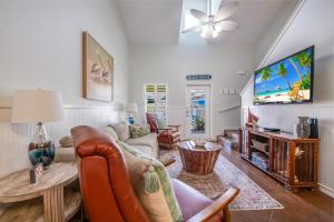 a living room with a couch and a tv at Pirates Bay #118 The LUV Shack poolfront townhome in Port Aransas