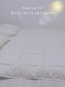 ein weißes Bett in einem Zimmer mit einem Wandschreiben in der Unterkunft A-one in Seoul