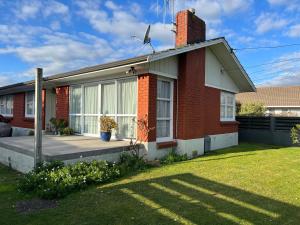 a red brick house with a large window and a lawn at Glenview home in Hamilton