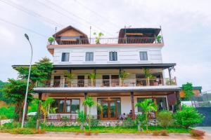 een groot wit gebouw met een balkon. bij BAO AN RESORT & BUNGALOW in Hòa Bình