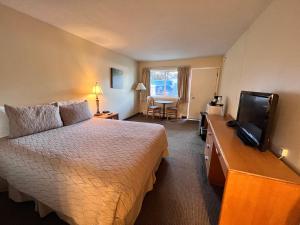 um quarto de hotel com uma cama e uma televisão de ecrã plano em Timbers INN and Suites em Ashland