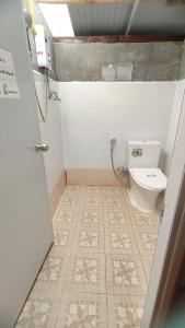 a bathroom with a toilet and a tiled floor at โฮมสเตย์ เนเจอร์ เดอ สะปัน in Ban Huai Ti