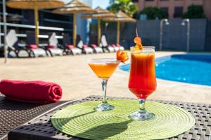 two cocktails sitting on a table next to a pool at Hotel Nuevo Boston in Madrid