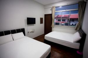 una piccola stanza con due letti e una finestra di Hom2rex Kuching Homestay Taman Timberland a Kuching