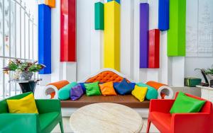 a room with a couch with colorful chairs and a table at The Color Kata in Kata Beach