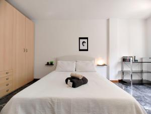 Un dormitorio con una cama blanca con un animal de peluche. en Primo Maggio en Udine