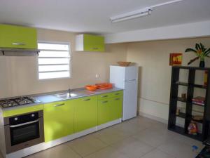 cocina con armarios verdes y nevera blanca en Logement dans un lieu calme et verdoyant à proximité de tout avec Jacuzzi!!!, en Basse-Terre